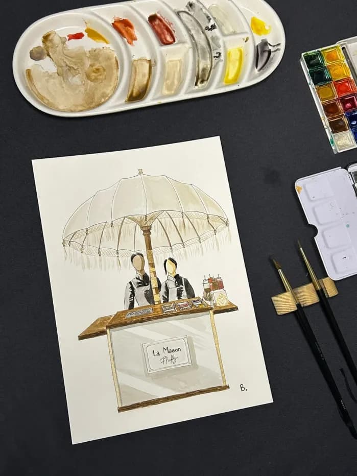 Aquarelle du comptoir La Maison Fluffy entourée du matériel de peinture