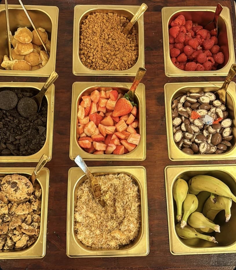 Composition de fruits, biscuits et toppings dans les bacs dorés du comptoir